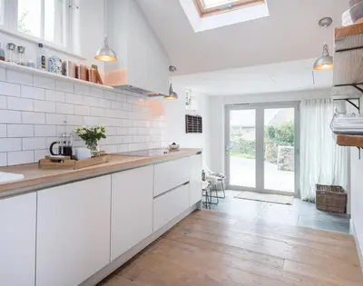 a kitchen with white cabinets and a wooden floor at Albany in Port Isaac