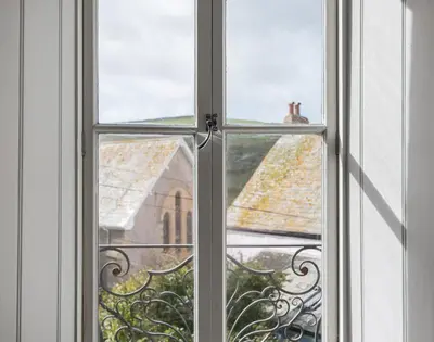 an open window with a view of a church at Albany in Port Isaac