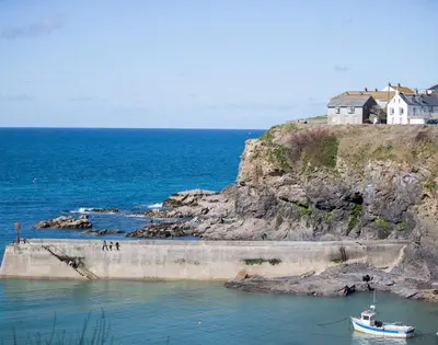 a boat in the water next to a house at Albany in Port Isaac