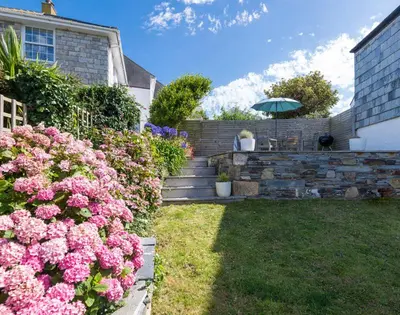 a garden with pink flowers and an umbrella at Albany in Port Isaac