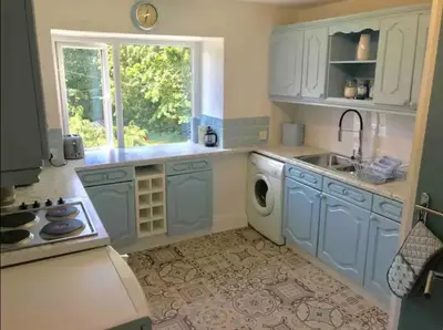 a kitchen with blue cabinets and a sink and a window at A woodland retreat - Apartment in converted mill in Helston