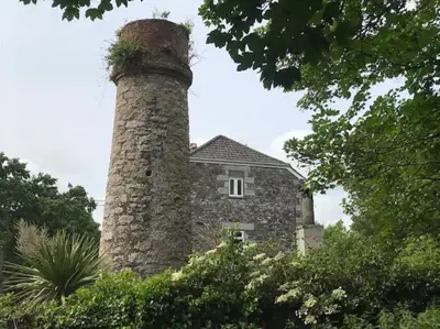 an old stone building with a plant on top of it at A woodland retreat - Apartment in converted mill in Helston
