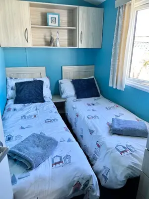 two beds in a room with blue walls at Newquay Bay Resort - Sea Breeze 61 in Newquay