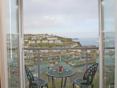 a balcony with a table with two glasses of wine at Wheal Kendall in St Austell