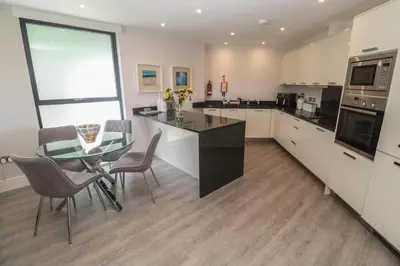 a kitchen with a glass table and a dining room at Peninsula Apartment 2 in St Ives