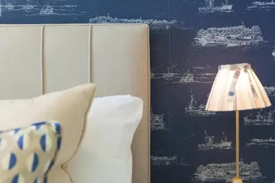 a lamp sitting next to a bed with a blue wall at Peninsula Apartment 2 in St Ives