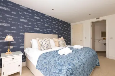 a bedroom with a bed and a blue wall at Peninsula Apartment 2 in St Ives