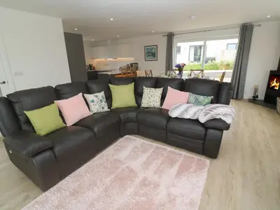 a black leather couch with colorful pillows in a living room at 3 Praa Cove in Penzance