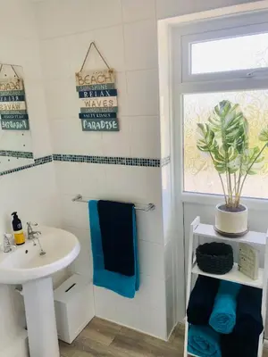 a white bathroom with a sink and a window at Detached, peaceful, spacious with easy access and very large garden in Wadebridge