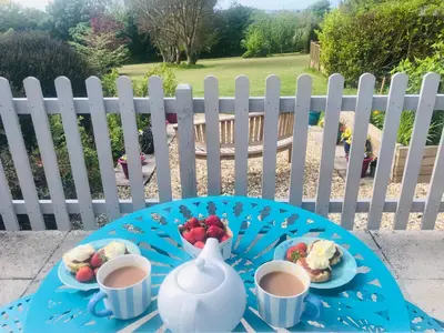 a blue table with two cups of tea and fruit on it at Detached, peaceful, spacious with easy access and very large garden in Wadebridge