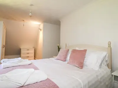 a bedroom with a white bed with pink and white pillows at Chyrosen in Redruth