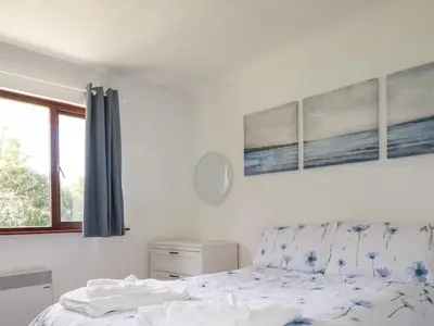 a bedroom with a bed and three paintings on the wall at Chyrosen in Redruth