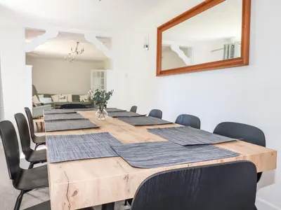 a dining room table with black chairs and a mirror at Chyrosen in Redruth