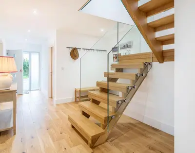 a staircase in a living room with glass railing at Artemis in Saint Minver