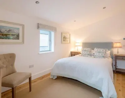 a bedroom with a bed and a chair and a window at Artemis in Saint Minver