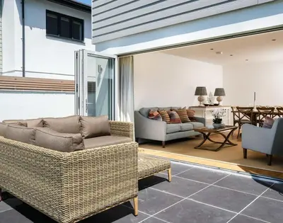 a living room with wicker furniture and a table at Artemis in Saint Minver