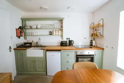 a kitchen with green cabinets and a sink and a table at The Old Pirates Lookout in Falmouth