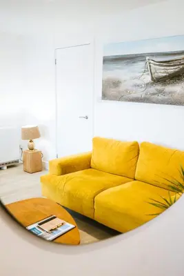 a yellow couch in a living room with a painting at The Old Captains Lookout in Falmouth