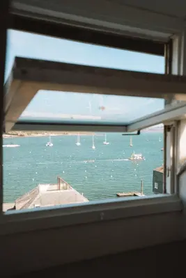 a window with a view of the water with boats at The Old Captains Lookout in Falmouth