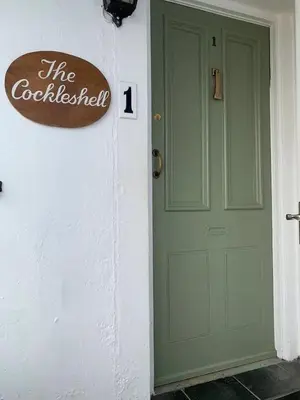a green door with a sign on the side of a building at Cockleshell Cottage in Falmouth