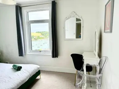 a bedroom with a bed and a desk and a window at Cockleshell Cottage in Falmouth
