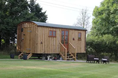 a wooden house with a staircase in a yard at Hare's Hut in Saint Clement