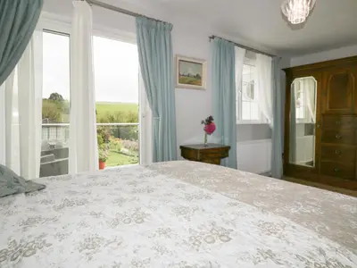 a bedroom with a large bed and a large window at Creekside House in Fowey