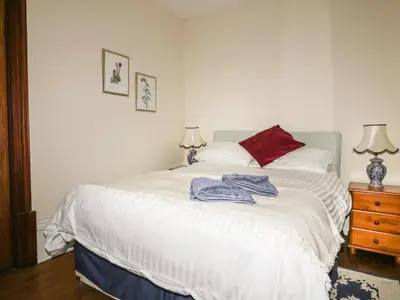 a bedroom with a white bed with a red pillow at Creekside House in Fowey