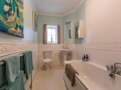 a bathroom with a tub and a toilet and a sink at Creekside House in Fowey
