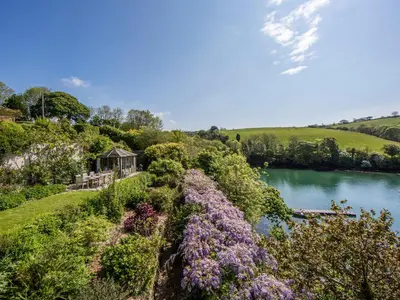 a garden with purple flowers and a river at Creekside House in Fowey