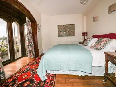 a bedroom with a bed and a large window at Creekside House in Fowey
