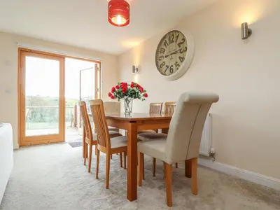 a dining room table with chairs and a clock on the wall at Maple in Falmouth