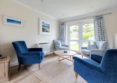 a living room with blue chairs and a table at Silverdale in Wadebridge