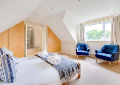a bedroom with a bed and two blue chairs at Silverdale in Wadebridge