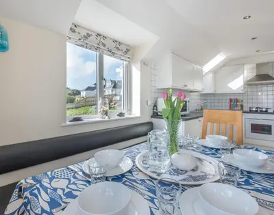 a kitchen with a table with plates and a vase of flowers at Polmorla in Polzeath