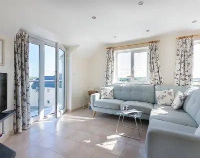 a living room with a blue couch and windows at Polmorla in Polzeath