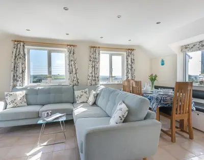 a living room with a blue couch and a table at Polmorla in Polzeath