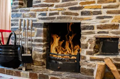 a brick fireplace with a fire in it at Pencreek in Padstow