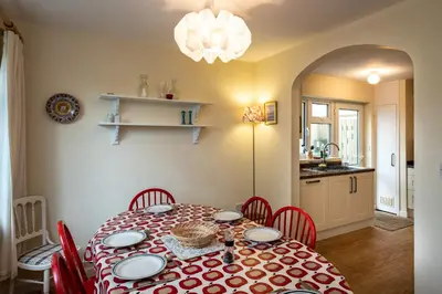 a dining room with a table and chairs and a kitchen at Pencreek in Padstow