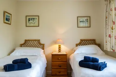 two twin beds in a bedroom with blue pillows at Pencreek in Padstow