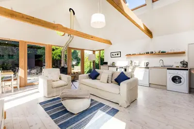 a living room with two couches and a kitchen at Greystones Studio in Polzeath