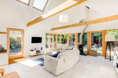 a living room with white furniture and windows at Greystones Studio in Polzeath