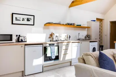 a kitchen with white appliances and a couch at Greystones Studio in Polzeath