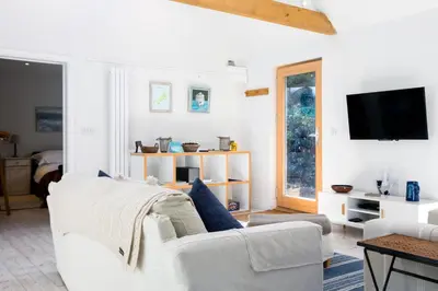 a living room with a white couch and a tv at Greystones Studio in Polzeath