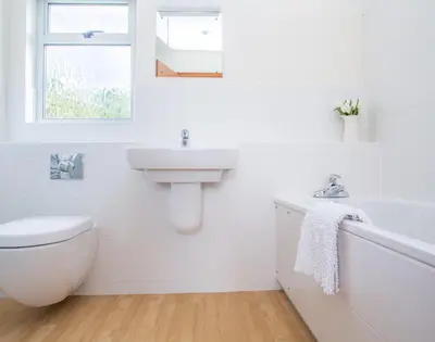 a white bathroom with a sink and a toilet at Rosevallen in Polzeath