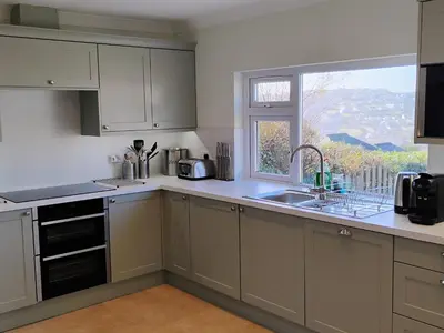 a kitchen with white cabinets and a sink and a window at Chy-An-Var in Polzeath