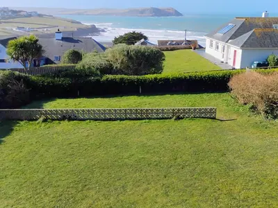 a grassy yard with a bench in front of a house at Chy-An-Var in Polzeath