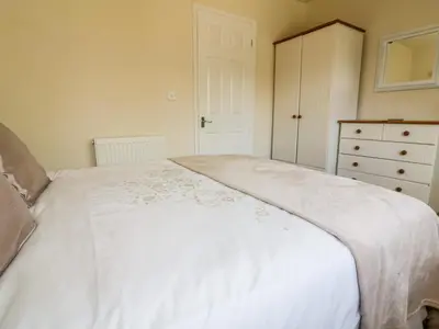a bedroom with a white bed and a dresser at 49 Atlantic Reach in Newquay