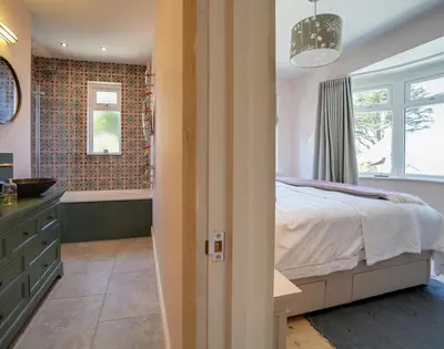 a bedroom with a bed and a bathroom with a tub at Trevanion in Saint Minver