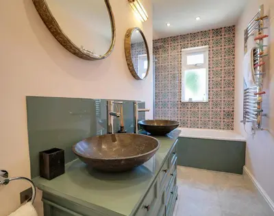 a bathroom with a sink and two mirrors on the wall at Trevanion in Saint Minver
